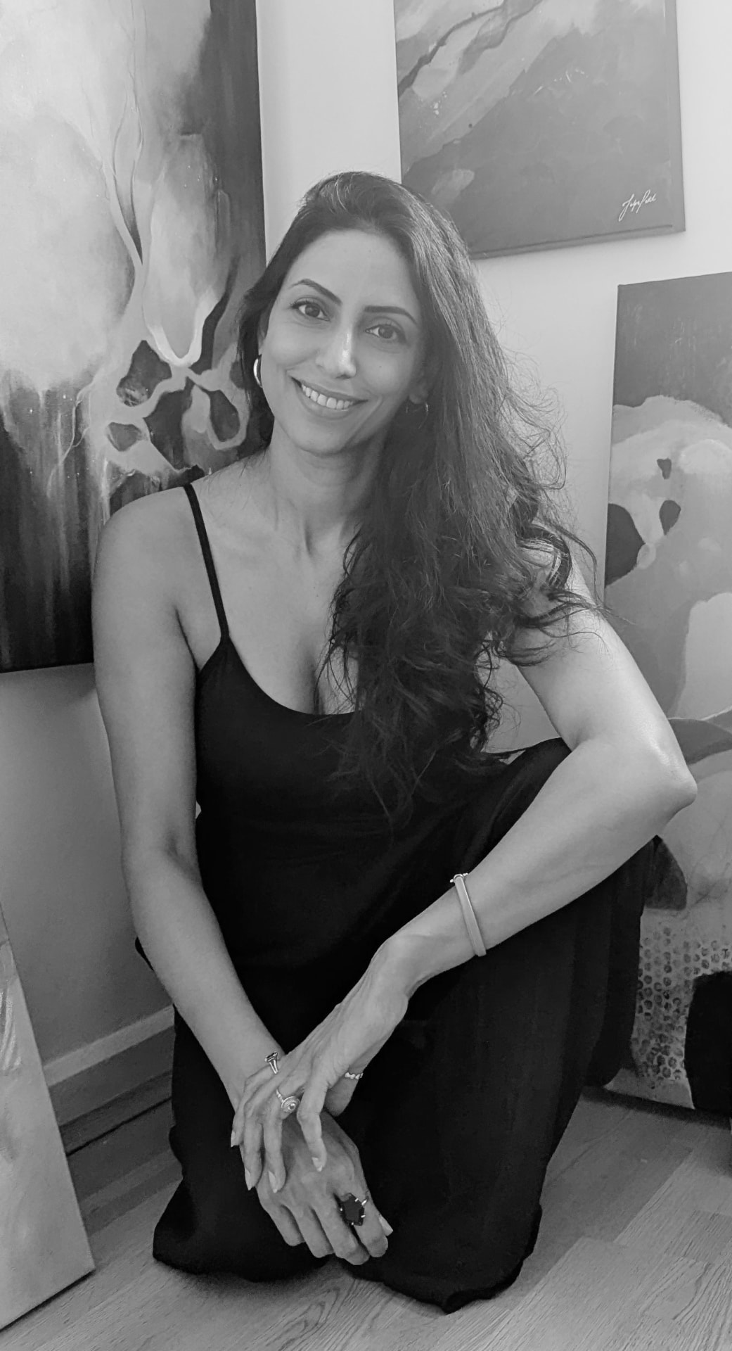 Jalpa Patel seated in her studio surrounded by her abstract paintings